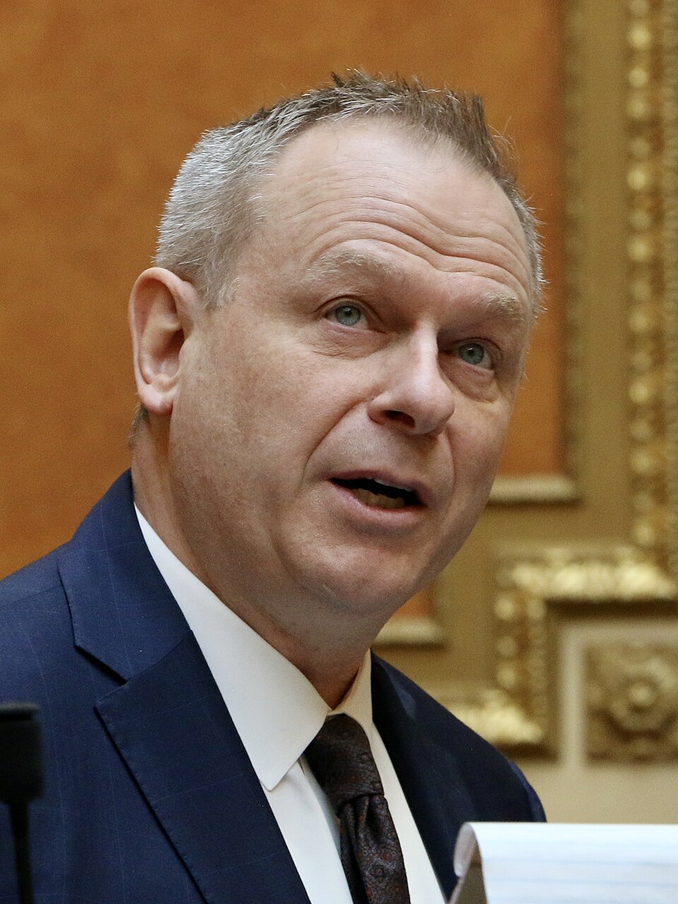 Doug Owens wearing a blue suit and tie in the House chamber.
