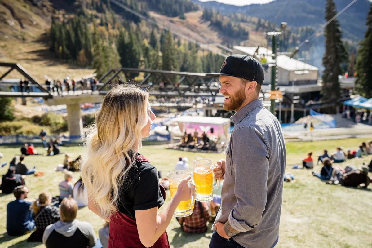 Two visitors holding drinks at a summer outdoor gathering in the Cottonwood mountains