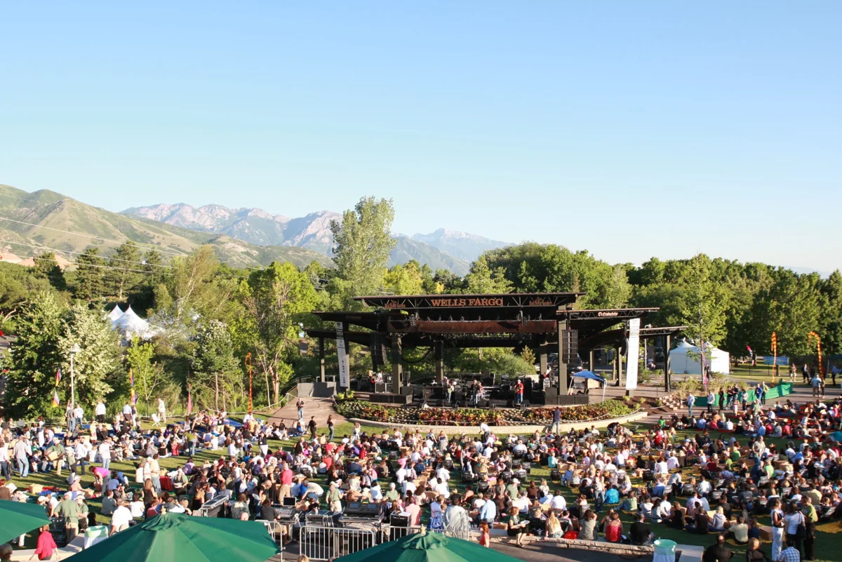 Crowds facing the outdoor stage at Red Butte Garden, with mountains behind