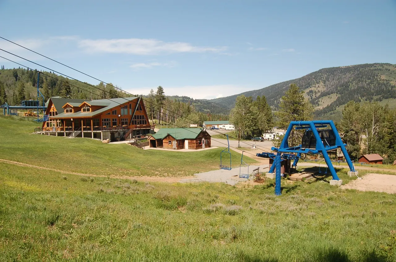 Looking down a green summer ski slope at Beaver Mountain in Logan Canyon, with the Face Lift chairlift, the day lodge and ticket cabin below