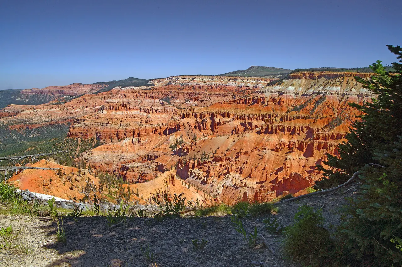 The eroded orange and white amphitheater of Cedar Breaks National Monument beneath a blue sky