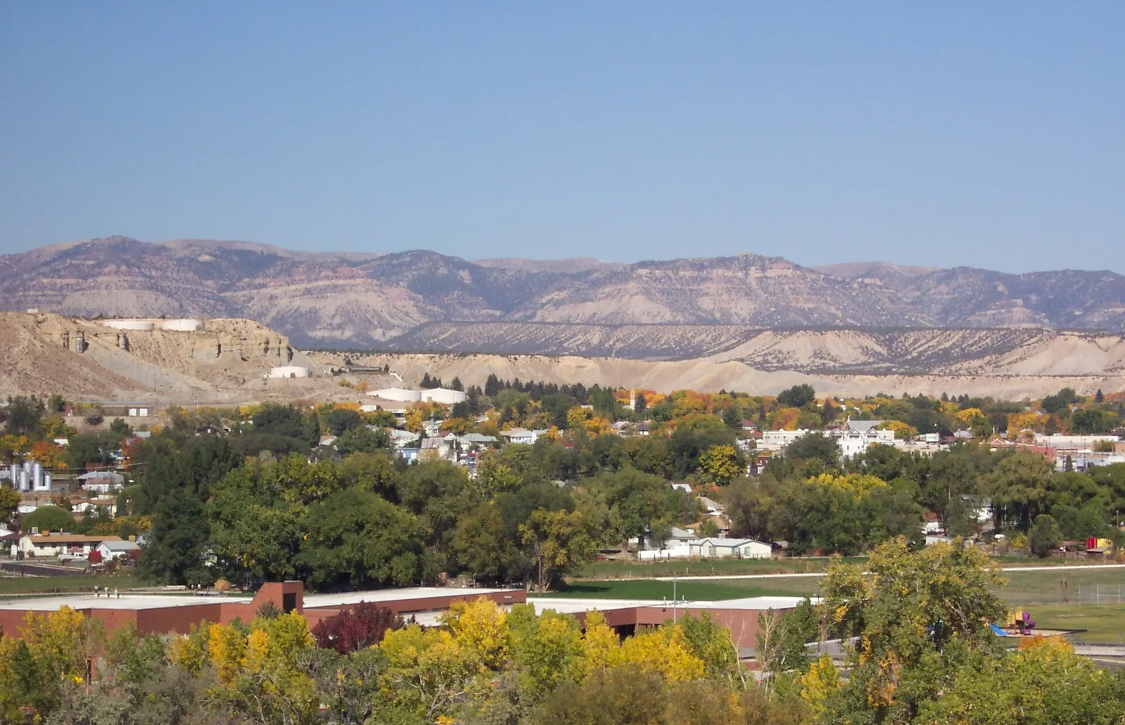Buildings and trees in Price with dry hills beyond