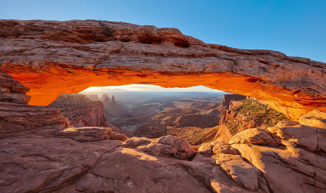 Sunrise glowing on the underside of Mesa Arch, framing the canyon country below in Canyonlands National Park
